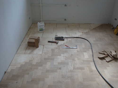 Laying piece parquet with a Christmas tree is the middle of the room